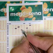 Homem apostando na Mega-Sena 2864 em uma lotérica com bilhete na mão