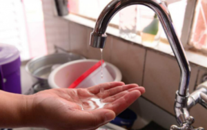 Pessoa coleta gotas de água de uma torneira quase seca durante corte no abastecimento