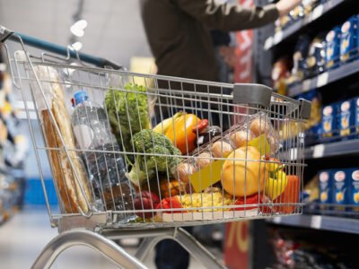 Consumidores fazendo compras em supermercado com prateleiras de alimentos