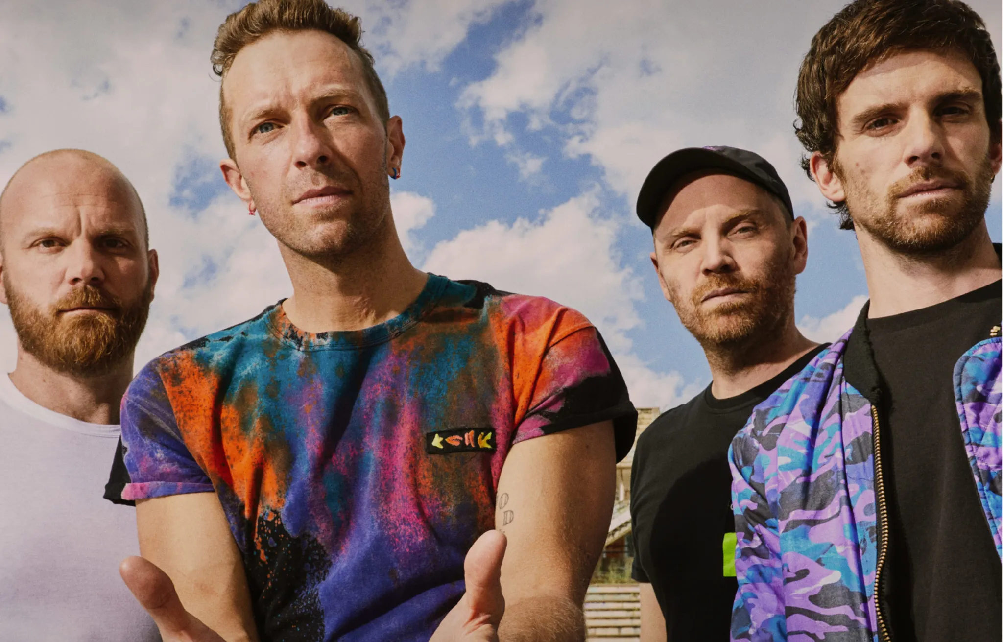 Imagem dos integrantes da banda Coldplay durante apresentação ao vivo com luzes coloridas