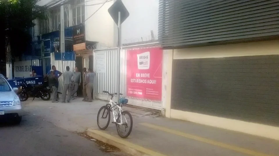 Imagem do local da tragédia com trabalhadores visivelmente abalados após morte de colega em obra escolar