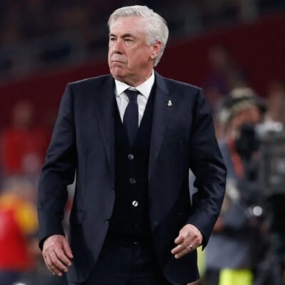 Técnico Carlo Ancelotti, de terno, à beira do campo durante jogo do Real Madrid