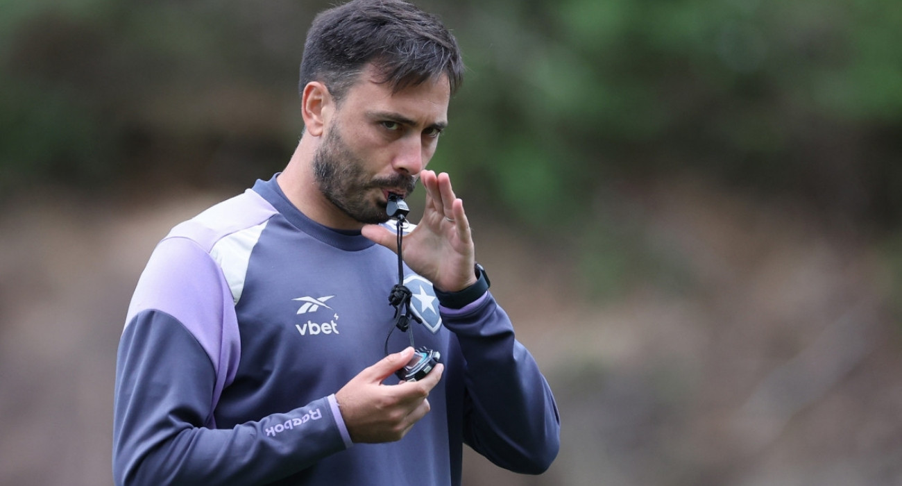 Comissão técnica do Botafogo e planejamento de contratações para 2026 Membro da comissão técnica do Botafogo, possivelmente um treinador ou preparador físico, usando um apito durante um treino. Ele veste um agasalho com o escudo do clube, simbolizando o trabalho e a preparação do time