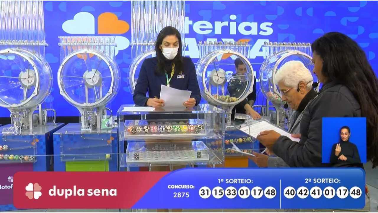 Funcionária Denise, da Loterias Caixa, juntamente com as auditoras do público, senhoras Loreta Rodrigues e Maria Albuquerque, realizando o procedimento de conferência e validação do número das bolas sorteadas correspondentes às dezenas que apontam o resultado do concurso 2875 da Dupla Sena | Reprodução/Youtube/Loterias Caixa