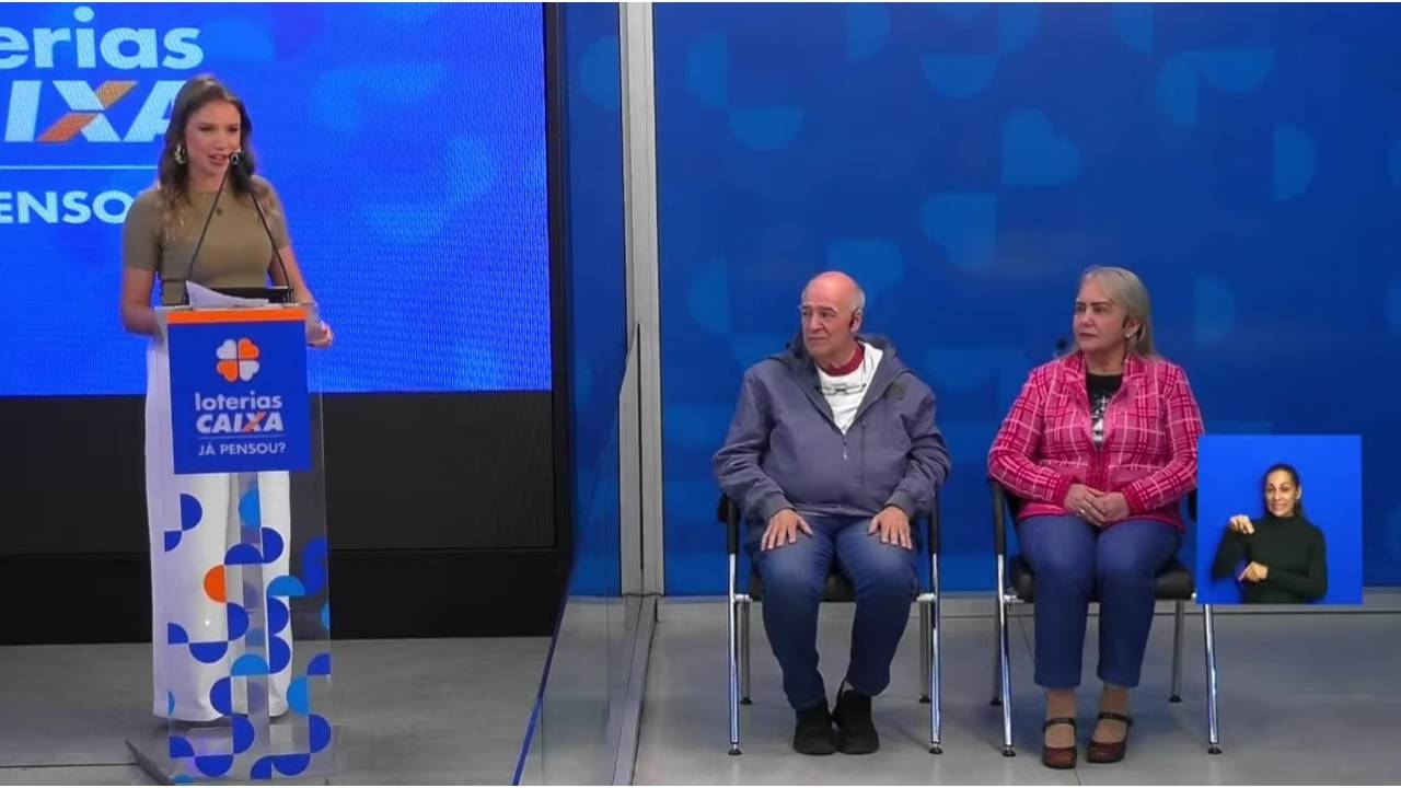 A imagem mostra o auditor Luís Casamaior e a auditora Lindaura Moraes sentados, com a apresentadora Nadiara Pereira, de pé, à esquerda (na imagem). Eles representaram o público das Loterias Caixa nos procedimentos e sorteios realizados no Espaço da Sorte, em São Paulo, nesta Segunda-Feira | Reprodução/Youtube/@canalcaixa 