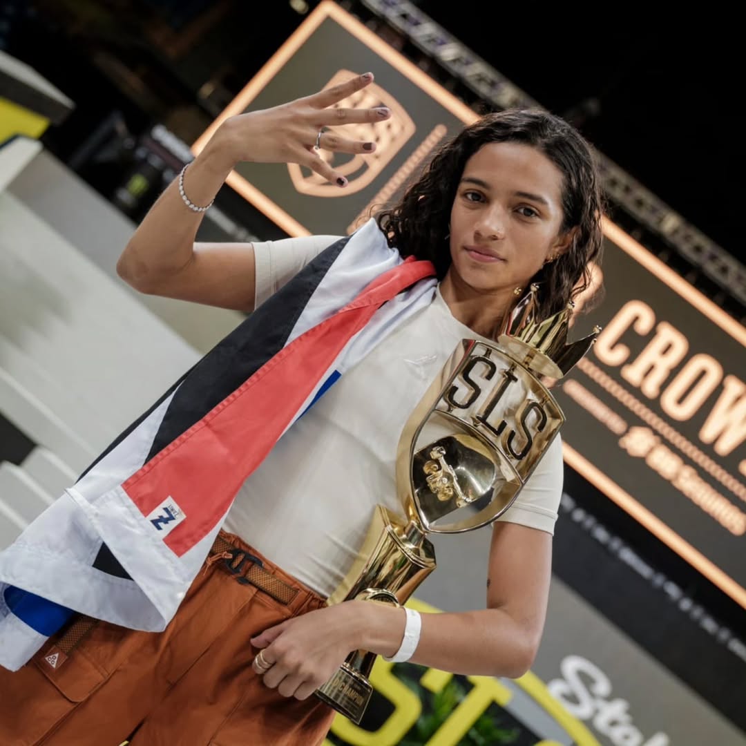 Rayssa Leal segurando troféu dourado da SLS e mostrando o número quatro com a mão em uma arena iluminada.