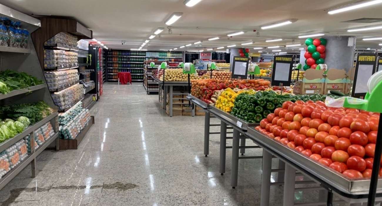 Prateleiras de supermercado lotadas com produtos natalinos e clientes fazendo compras com carrinhos