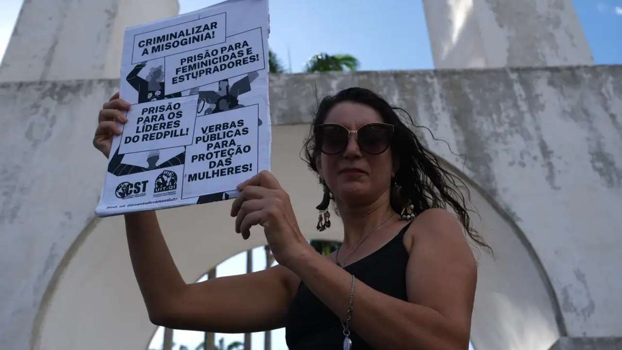 Manifestantes seguram cartazes contra a violência contra LGBTQIA+ e feminicídio nos Arcos da Lapa, Rio de Janeiro.