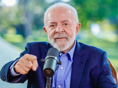 Presidente Lula falando diante de um microfone durante entrevista; destaque para matéria sobre a LDO 2026, que aguarda sanção.