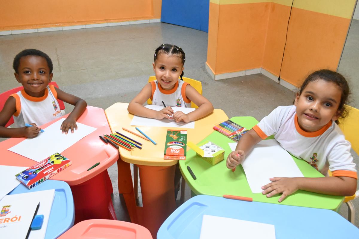 Alunos novos realizando atividades escolares em mesas coloridas, representando o ingresso em novas vagas da educação pública de Niterói. Alunos novos realizando atividades escolares em mesas coloridas, representando o ingresso em novas vagas da educação pública de Niterói.