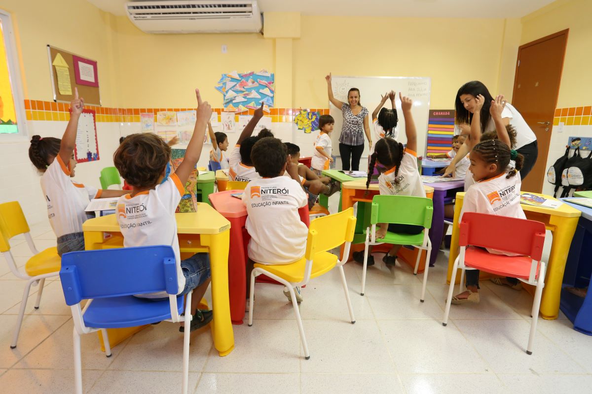 Professora orientando crianças em sala de aula da rede municipal de Niterói durante abertura de novas vagas para 2026.
