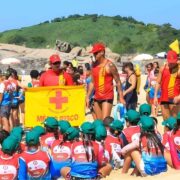 Crianças participam de simulação de primeiros socorros durante as inscrições do Projeto Botinho 2026 em Niterói e Maricá, com orientação direta dos guarda-vidas.