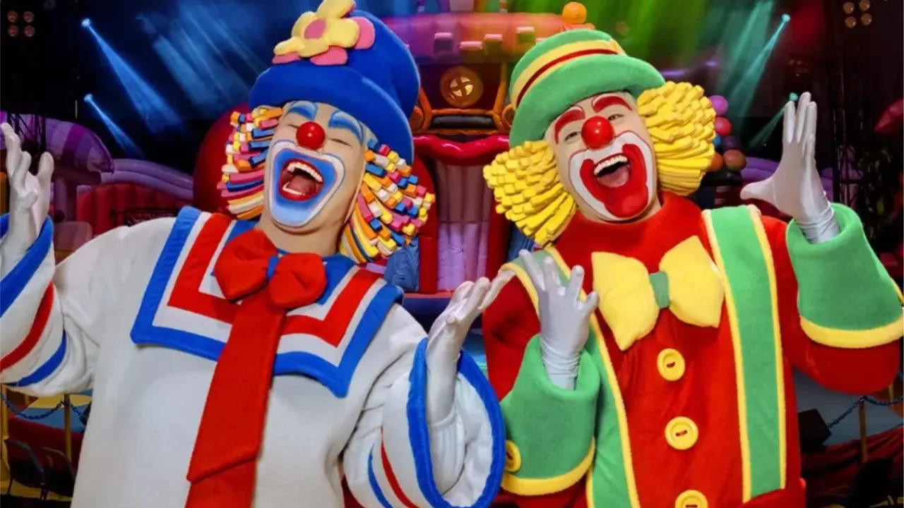 Patati e Patatá se apresentam em circo infantil com cenário colorido e personagens no palco