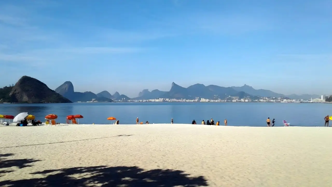 Vista de Niterói sob céu com sol entre nuvens durante previsão do tempo para o município