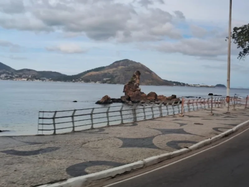 Orla de Niterói durante período de vento, com árvores e vegetação movimentadas pelas rajadas e o mar ao fundo. O município recebeu novo alerta de ventos costeiros às 8h30 deste domingo e permanece também sob aviso de vendaval