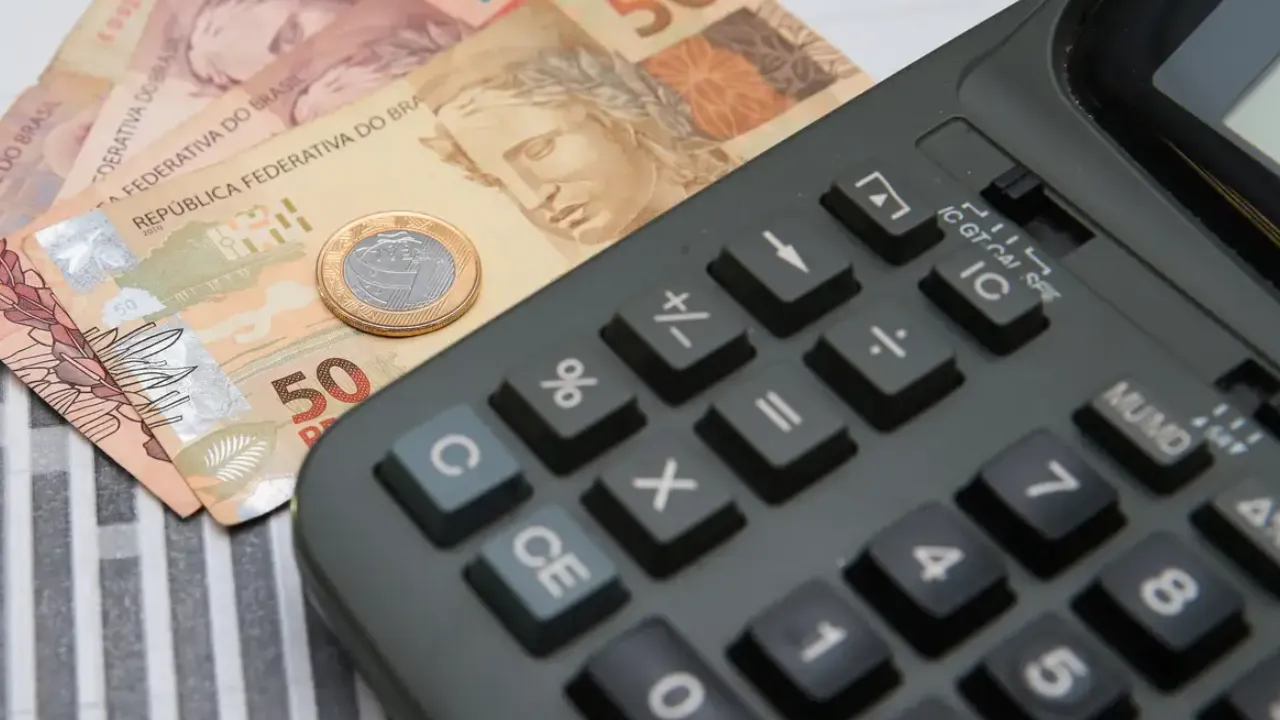 Aplicativo Meu INSS aberto em celular ao lado de documentos e calculadora Aplicativo Meu INSS aberto em celular ao lado de documentos e calculadora