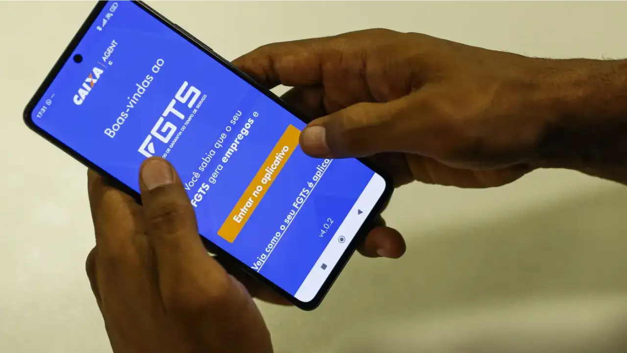 Trabalhador consulta no celular o lucro do FGTS 2026, que pode render R$ 18,68 para cada R$ 1 mil de saldo Trabalhador consulta no celular o lucro do FGTS 2026, que pode render R$ 18,68 para cada R$ 1 mil de saldo