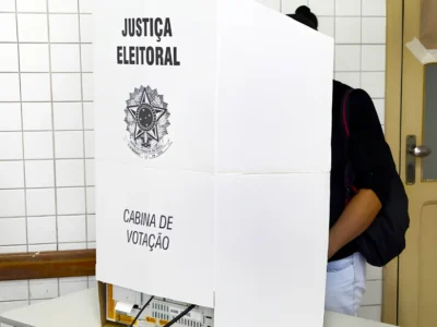 Mulher em cabina de votação em fotografia que ilustra reportagem sobre total de eleitores que poderão votar no Brasil nas eleições de outubro de 2026