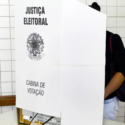 Mulher em cabina de votação em fotografia que ilustra reportagem sobre total de eleitores que poderão votar no Brasil nas eleições de outubro de 2026