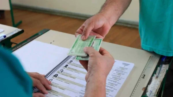 Eleitor apresenta documento ao mesário antes de votar nas Eleições 2026