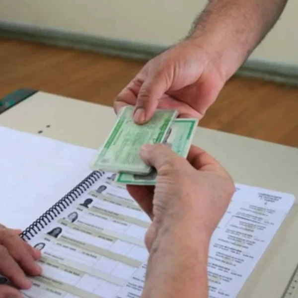 Eleitor apresenta documento ao mesário antes de votar nas Eleições 2026