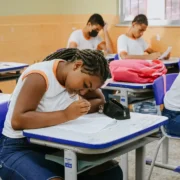 Estudante da rede municipal de Niterói sentado em sala de aula diante de caderno aberto