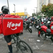 Aplicativos de compras e entregas exibidos em celular ao lado de medicamentos. A Anvisa revogou medidas contra iFood, Rappi, Mercado Livre, Americanas, Submarino e Shopee, enquanto prepara a regulamentação da Lei 15.357/2026 para o uso de plataformas digitais por farmácias e drogarias