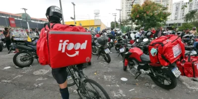 Aplicativos de compras e entregas exibidos em celular ao lado de medicamentos. A Anvisa revogou medidas contra iFood, Rappi, Mercado Livre, Americanas, Submarino e Shopee, enquanto prepara a regulamentação da Lei 15.357/2026 para o uso de plataformas digitais por farmácias e drogarias