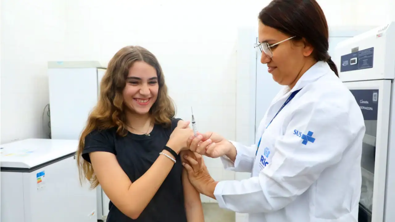 Adolescente recebe vacina de profissional de saúde durante campanha de multivacinação no Rio