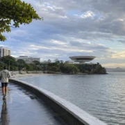 Imagem jornalística sobre a previsão do tempo em Niterói neste sábado, marcado por temperaturas amenas, muitas nuvens pela manhã e melhora gradual durante a tarde