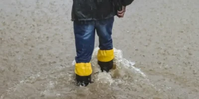 Pessoa caminha por rua alagada durante chuva forte no Rio Grande do Sul