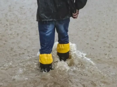 Pessoa caminha por rua alagada durante chuva forte no Rio Grande do Sul