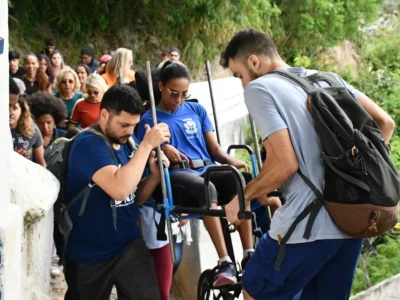 Imagem de pessoas ajudando uma pessoa com deficiência durante trilha em Niterói