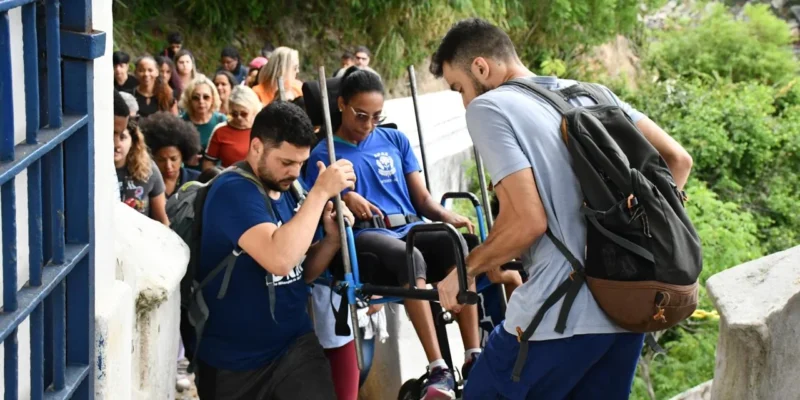 Imagem de pessoas ajudando uma pessoa com deficiência durante trilha em Niterói