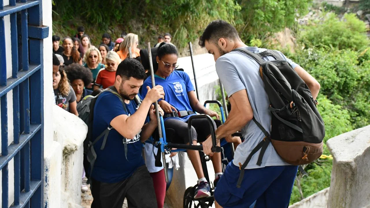 Imagem de pessoas ajudando uma pessoa com deficiência durante trilha em Niterói