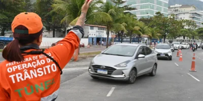 Agente da NitTrans sinaliza o trânsito enquanto veículos circulam por via de Niterói