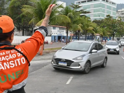 Agente da NitTrans sinaliza o trânsito enquanto veículos circulam por via de Niterói