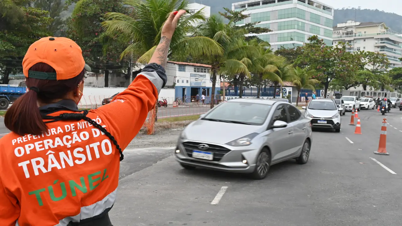 Agente da NitTrans sinaliza o trânsito enquanto veículos circulam por via de Niterói