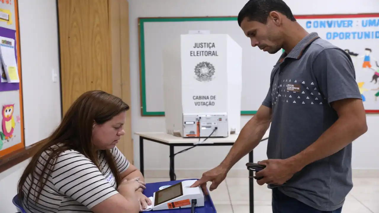 Eleitor é atendido por mesária em seção eleitoral durante votação