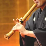 Músico toca shakuhachi, tradicional flauta japonesa de bambu.