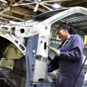 Trabalhadora atua na montagem da carroceria de um veículo em linha de produção automotiva.
