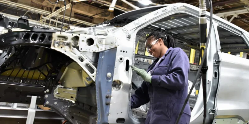 Trabalhadora atua na montagem da carroceria de um veículo em linha de produção automotiva.