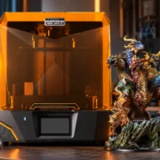 Impressora 3D Phrozen Sonic Mighty Revo 16K MAX ao lado de grande miniatura de dragão em resina.