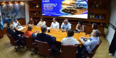 Reunião de equipes municipais de Niterói diante de painel do Plano Municipal de Preparação e Resposta ao El Niño