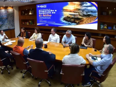 Reunião de equipes municipais de Niterói diante de painel do Plano Municipal de Preparação e Resposta ao El Niño