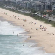 Vista panorâmica de praia de Niterói com faixa de areia, banhistas e ocupação urbana junto à orla
