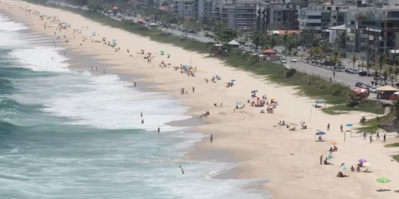 Vista panorâmica de praia de Niterói com faixa de areia, banhistas e ocupação urbana junto à orla