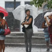 Pessoas usam guarda-chuvas durante chuva forte em área urbanaPessoas usam guarda-chuvas durante chuva forte em área urbana