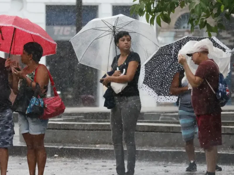 Pessoas usam guarda-chuvas durante chuva forte em área urbanaPessoas usam guarda-chuvas durante chuva forte em área urbana