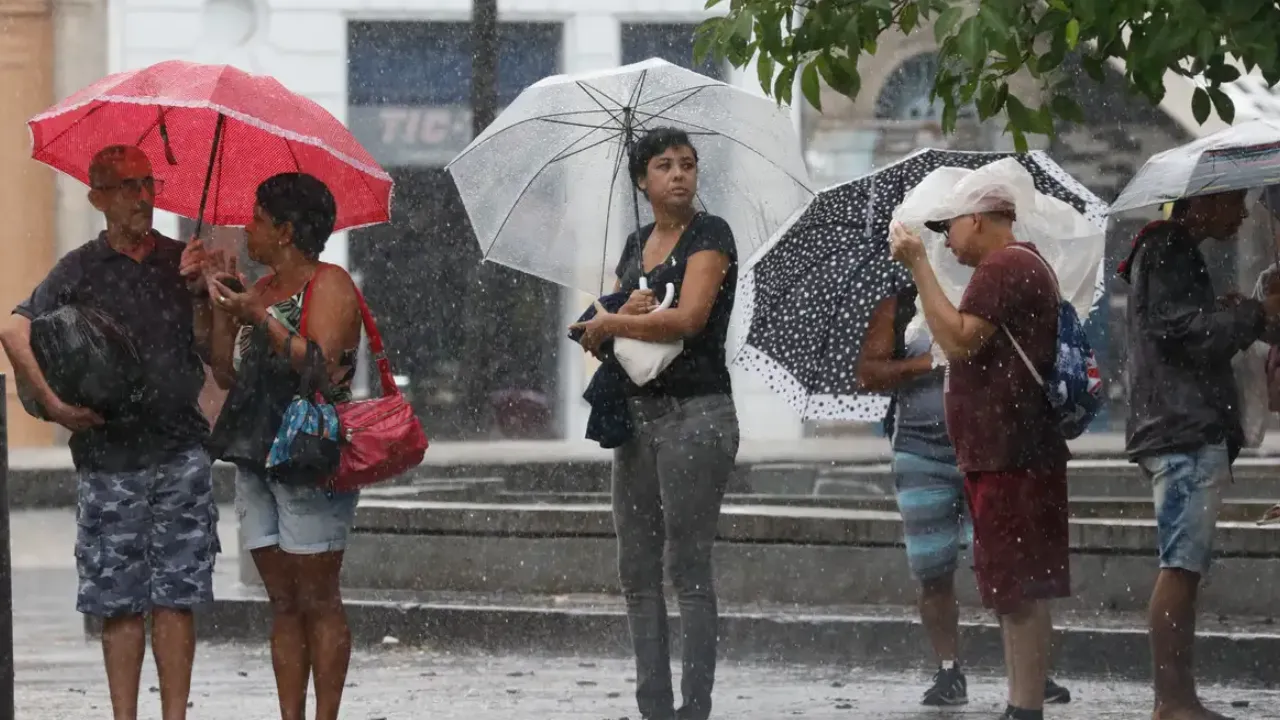 Pessoas usam guarda-chuvas durante chuva forte em área urbanaPessoas usam guarda-chuvas durante chuva forte em área urbana